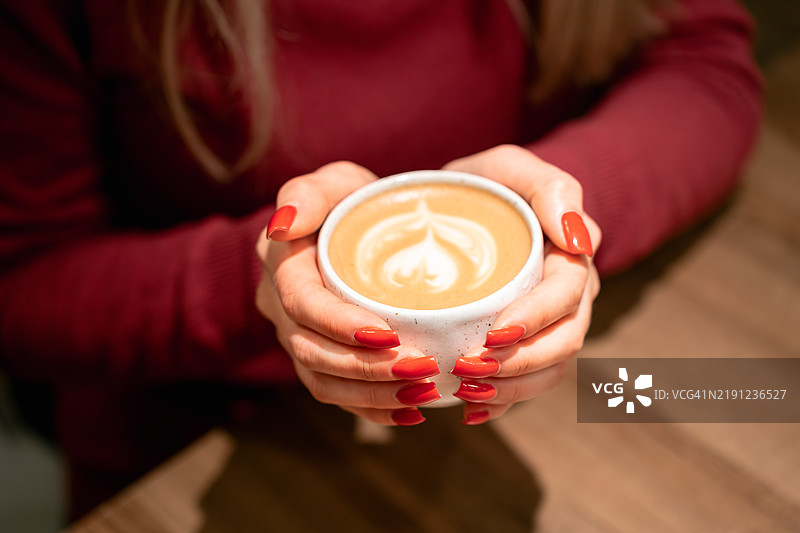 女人手持带有拉花的咖啡杯图片素材