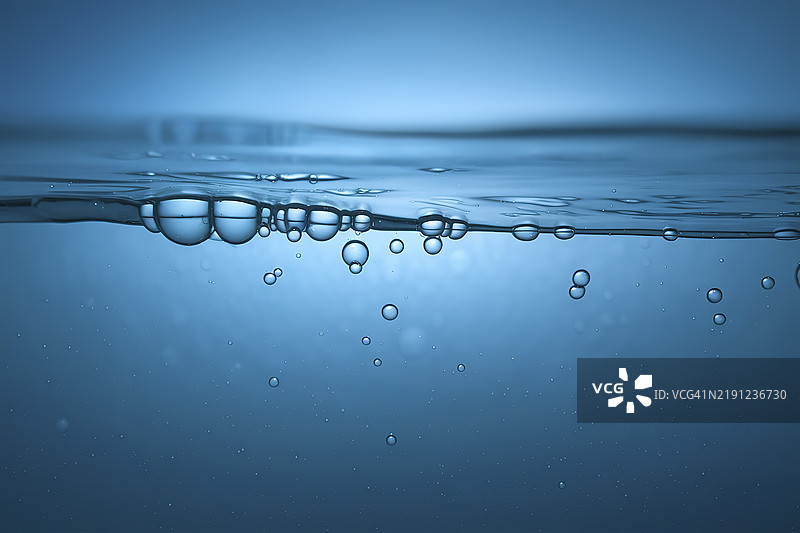 一幅抽象艺术作品，蓝色背景上漂浮着油泡的水面图片素材