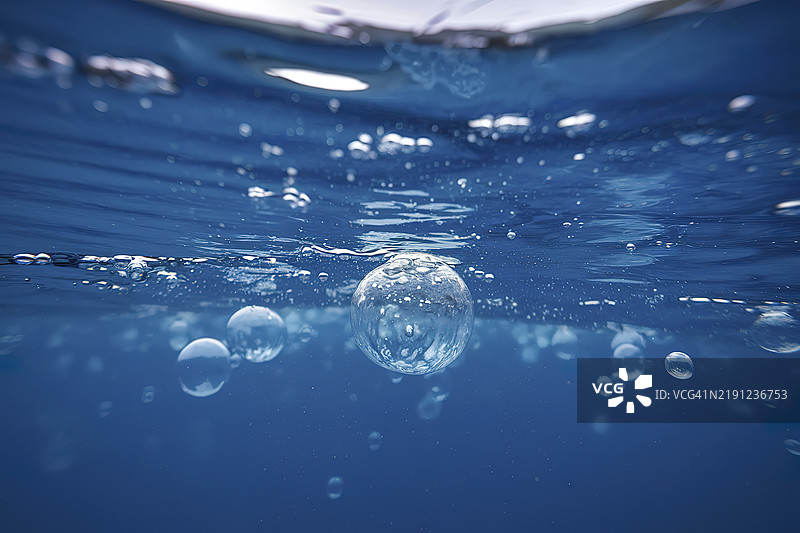 深蓝色的水下场景，前景和背景中漂浮着许多气泡图片素材