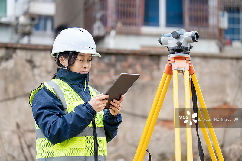 工程师正在使用测量相机在建筑工地上测量高度。图片素材