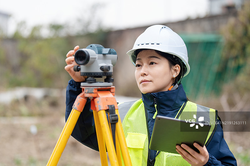 工程师正在使用测量相机在建筑工地上测量高度。图片素材