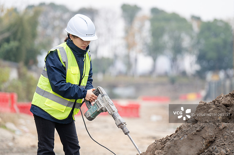 亚洲女性工人在道路施工中使用电锤图片素材