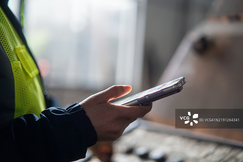 在工厂里使用智能手机的亚洲女性工程师图片素材