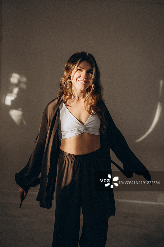 时尚年轻女性微笑着穿着舒适的家居服，在家中享受放松的时光图片素材