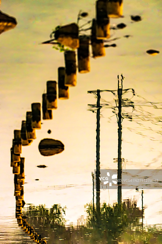 早晨水面上倒映的围栏和电线杆图片素材