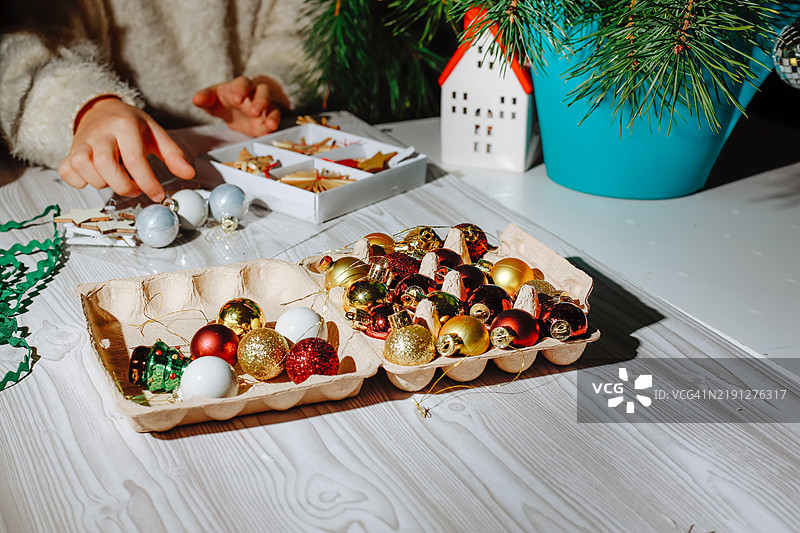 孩子们的手特写，正在摆放独特的圣诞装饰品：丝带、球饰和稻草工艺品，配以复古闪光效果。图片素材