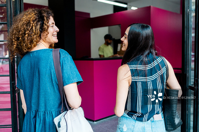 朋友们从后面看，正在交谈并走进一家商店图片素材