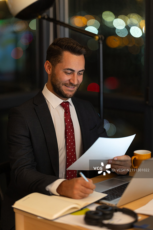 商人在办公室深夜加班阅读文件图片素材