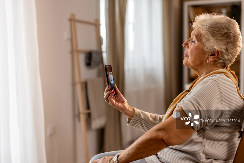 老年女性在舒适的家居环境中视频通话与亲人联系图片素材