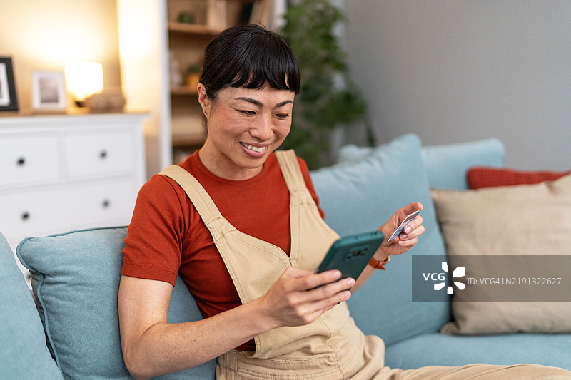 微笑的女性在家中网上购物图片素材