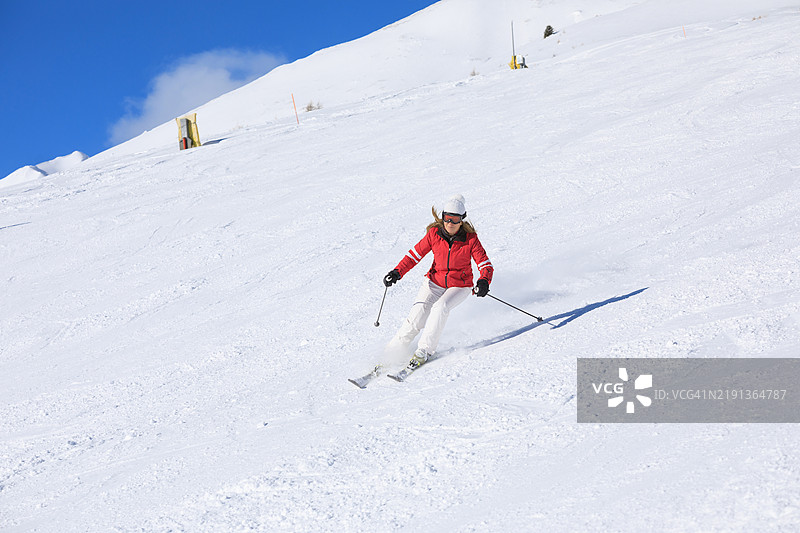 冬季运动，女性滑雪者在完美的滑雪坡道上高速滑雪，享受阳光明媚的塞拉隆达滑雪度假区。多洛米蒂超级滑雪区的雪山。意大利瓦尔加尔德纳滑雪度假村。图片素材