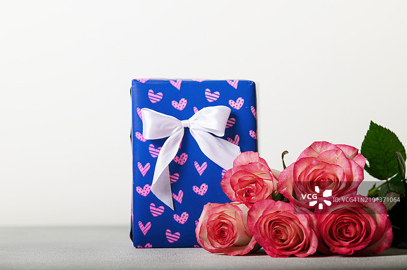 粉色玫瑰与蓝色礼品盒，白色丝带，简约背景图片素材