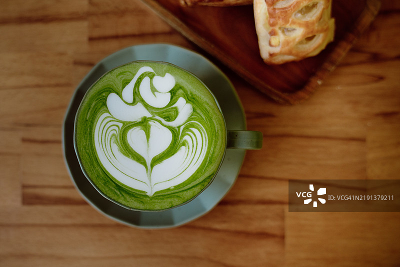 木盘上的自制抹茶拿铁和两个迷你苹果派的俯视图图片素材