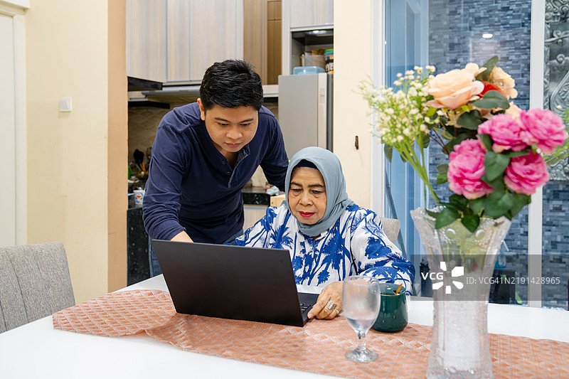 母亲和儿子在家使用笔记本电脑图片素材