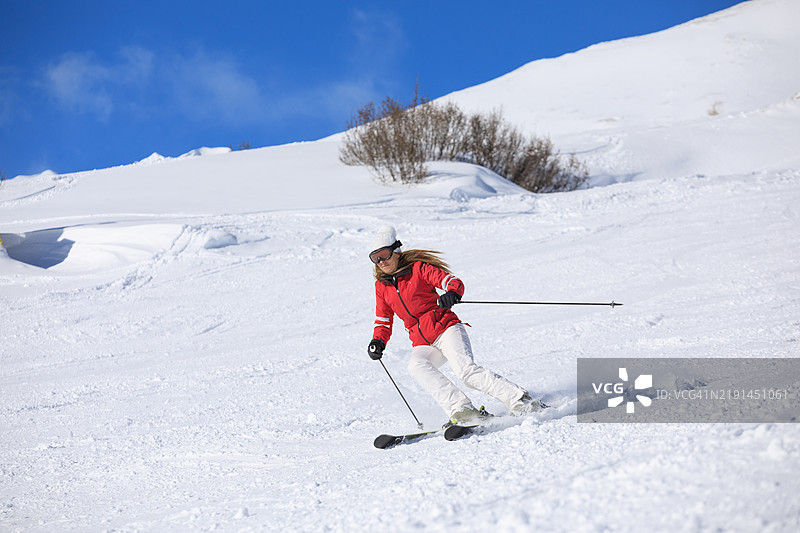 冬季运动，女性滑雪者在完美的滑雪坡道上高速滑雪，享受阳光明媚的塞拉隆达滑雪度假区。多洛米蒂超级滑雪区的雪山。意大利瓦尔加尔德纳滑雪度假村。图片素材