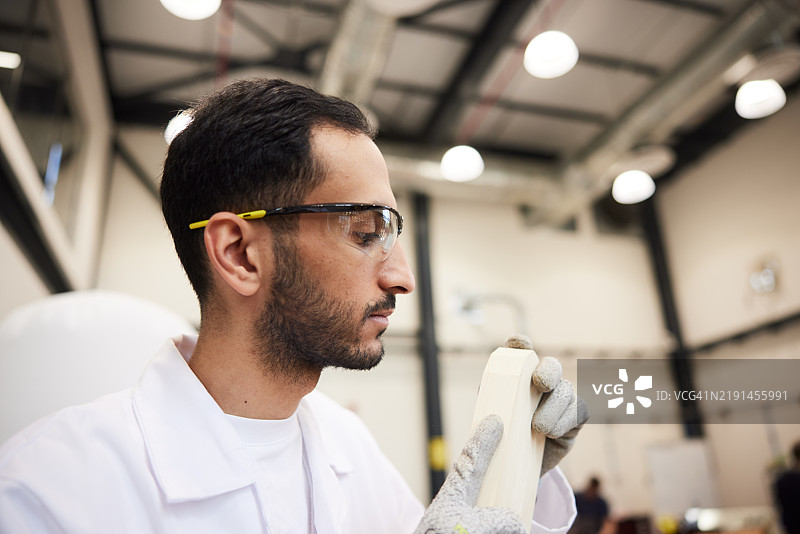 木工仔细检查打磨过的木条，关注每一个细节，寻找瑕疵。图片素材