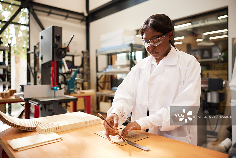 工匠专注于在工作室的刨花板上做出准确的切割标记。图片素材