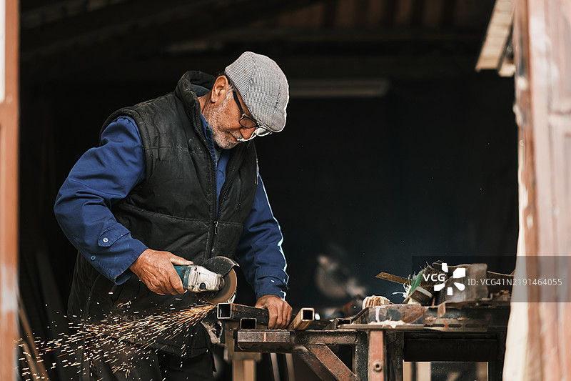 一位年长的男子在他的工作坊里磨削。图片素材