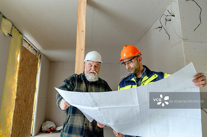 房主和建筑工人在公寓翻新期间分析蓝图图片素材