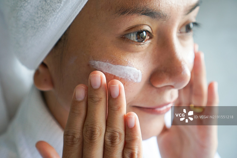 一位女性专注而温柔地涂抹护肤霜的特写镜头图片素材