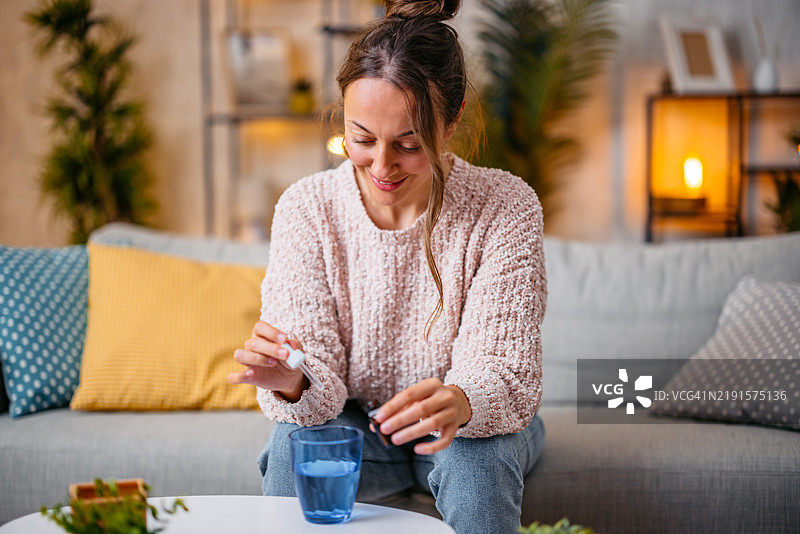 中年女性将药水滴入一杯水中图片素材
