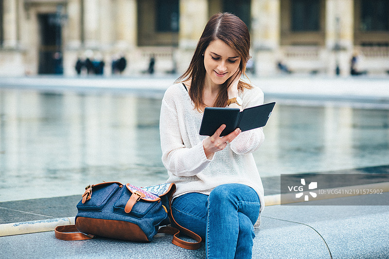 年轻女性在城市中阅读电子书图片素材