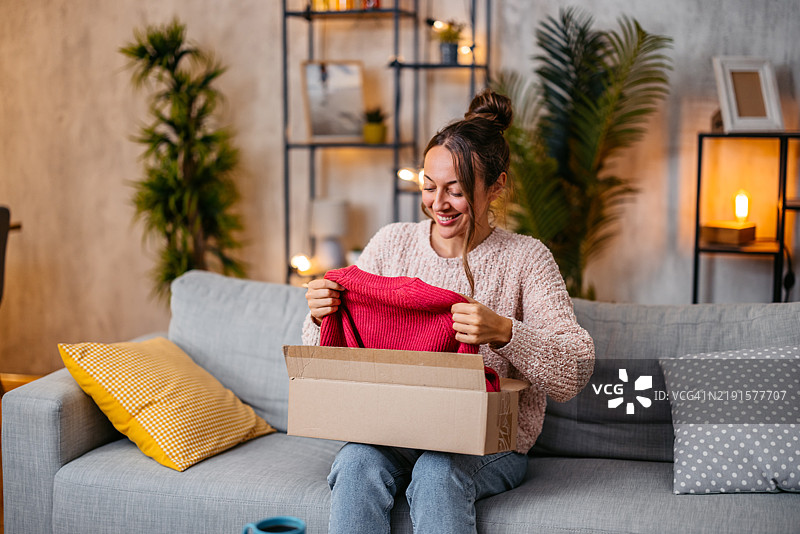 中年女性正在拆开她在线订购的新毛衣包裹图片素材