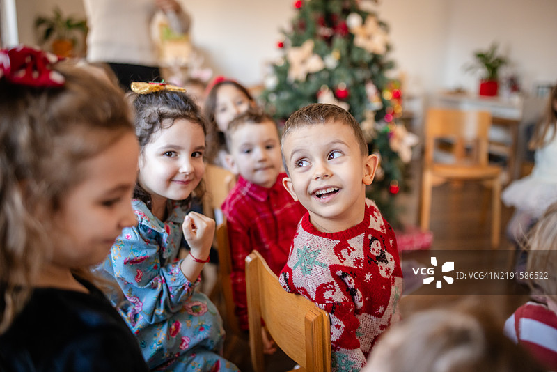 男孩们在装饰好的圣诞树旁微笑。图片素材