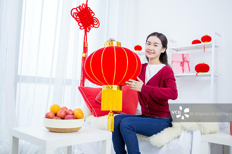 一位年轻女性手持红色中国灯笼。图片素材