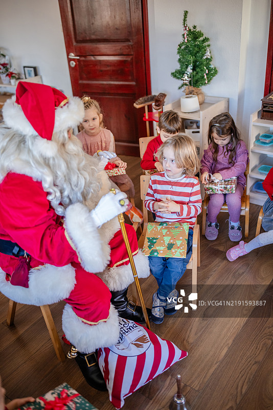 圣诞老人给兴奋的孩子们送礼物。图片素材