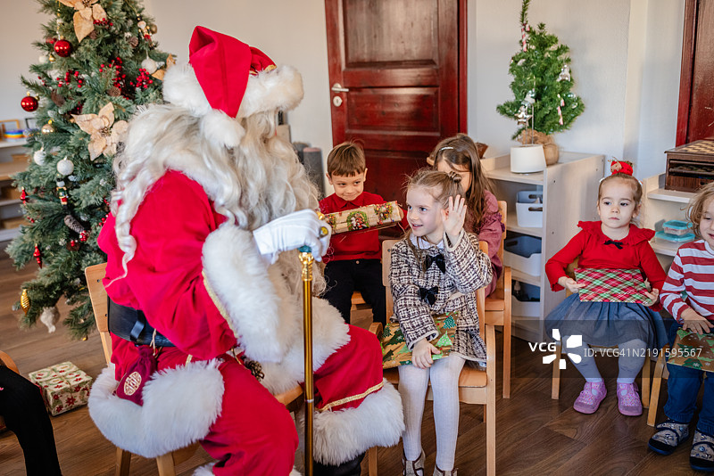 圣诞老人向孩子们分发礼物，在节日聚会上。图片素材