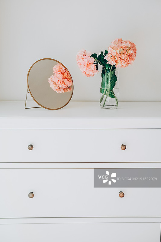 优雅的花卉装饰，粉色绣球花和白色梳妆台上的镜子，提供室内设计灵感图片素材