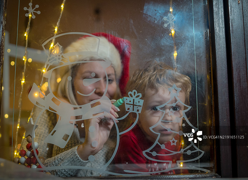 小男孩在冬天的窗户上画画图片素材