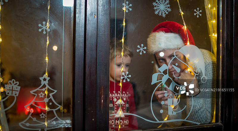 小男孩在冬天的窗户上画画图片素材