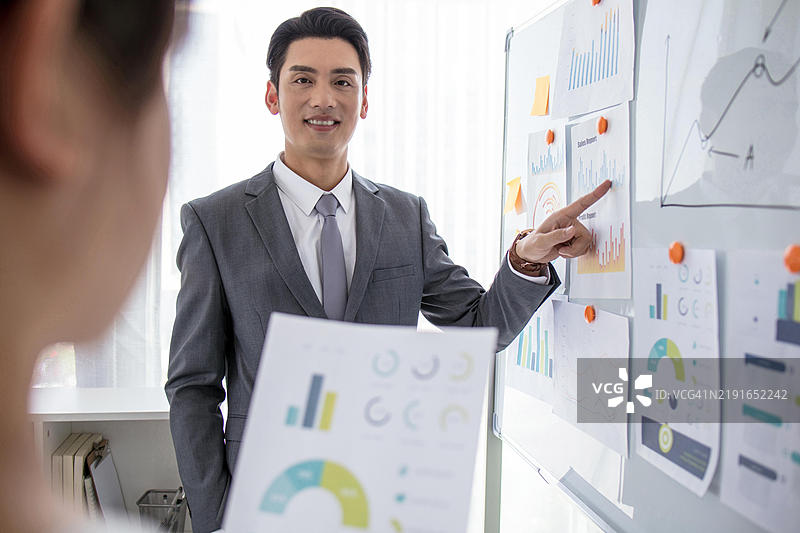 亚洲商人在办公室向女性同事做演示图片素材