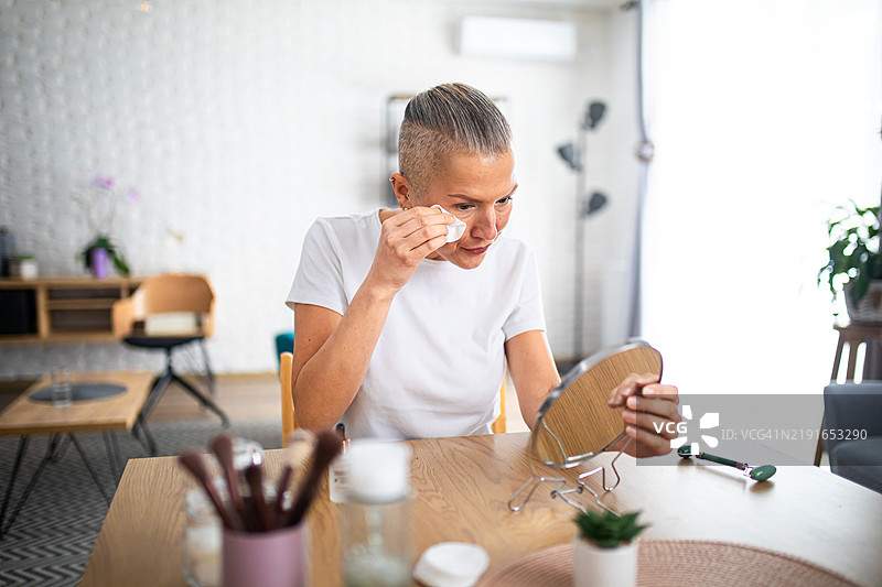 快乐的中年女性在家使用棉垫进行护肤图片素材