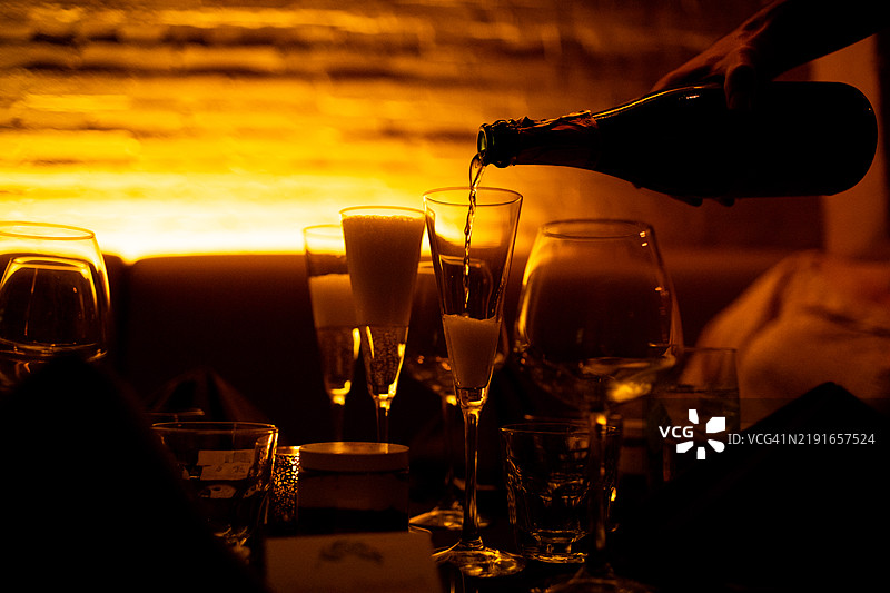 服务员在昏暗的酒吧里倒白葡萄酒入杯中图片素材