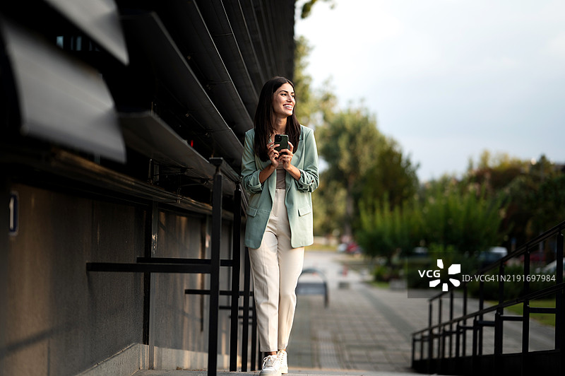 美丽的年轻女性在户外使用智能手机图片素材