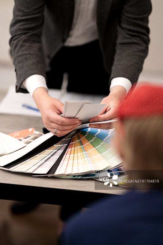 桌子上摆放着室内设计用的调色板。设计师在设计工作室中与客户咨询。客户选择墙面涂料样本，包括清漆、灰泥、背景、壁纸和外立面。图片素材
