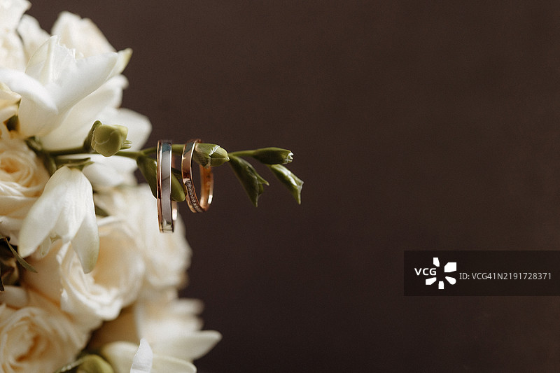 两枚金戒指挂在婚礼花束的一根枝条上特写镜头图片素材