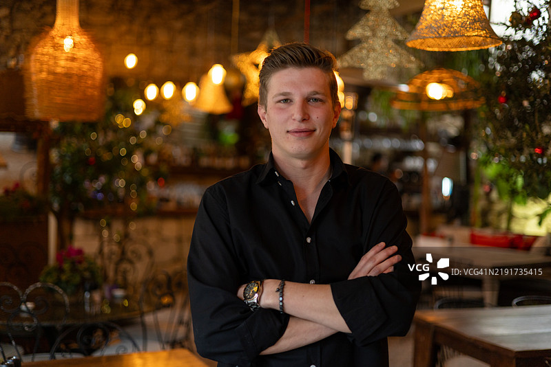 圣诞装饰餐厅中微笑并交叉双臂的餐厅经理图片素材