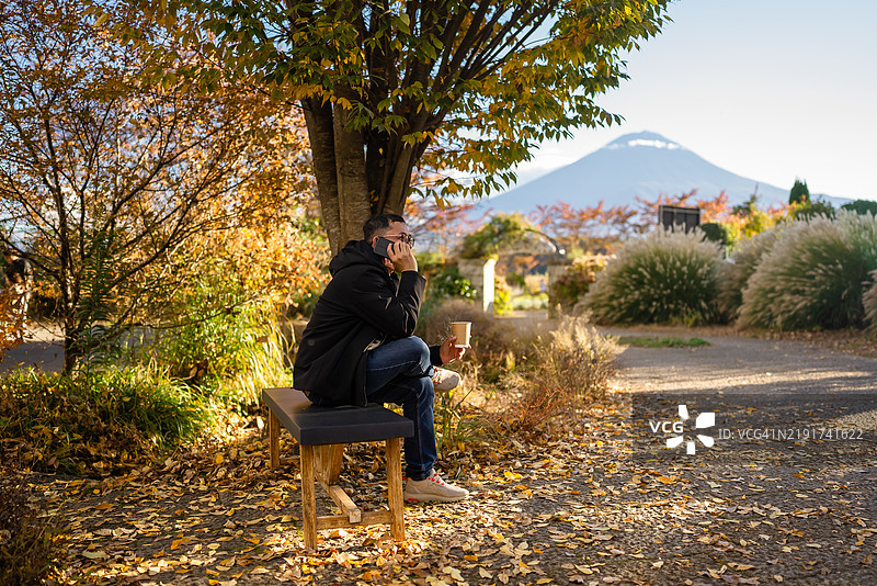 在公园长椅上打电话的男人图片素材