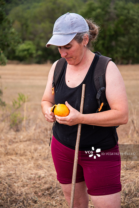 牧羊女在田野里剥橙子图片素材