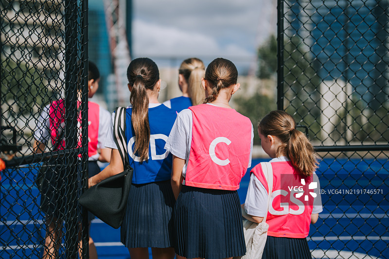 年轻的澳大利亚女子网球队员们从背后视角走向运动场，准备进行例行训练。图片素材