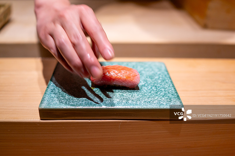 厨师在陶瓷盘上盛放一份金枪鱼寿司。图片素材