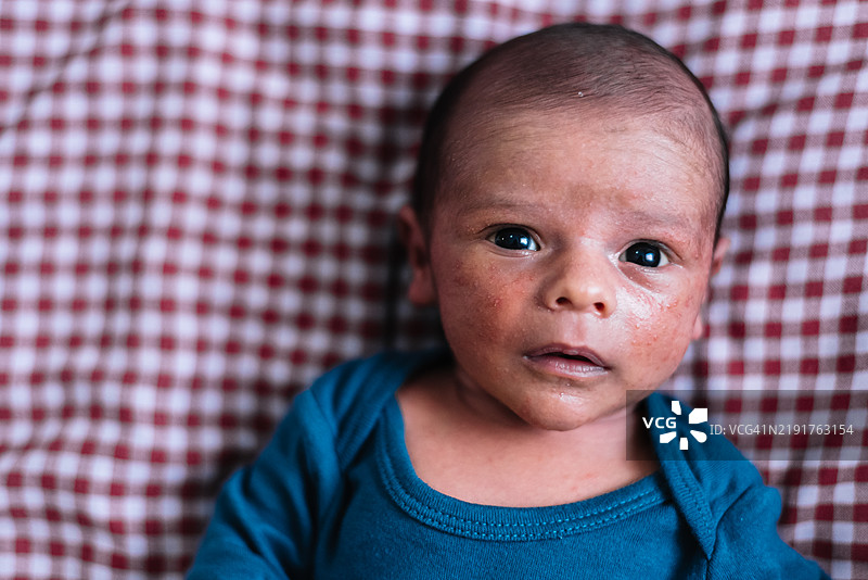 新生儿躺在床上的肖像。脸上有母乳的痕迹。图片素材