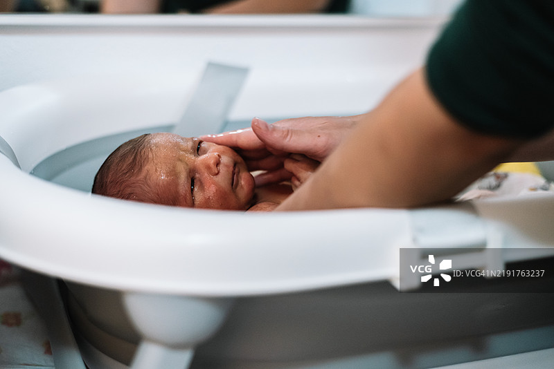 母亲正在给她的新生儿洗澡。图片素材