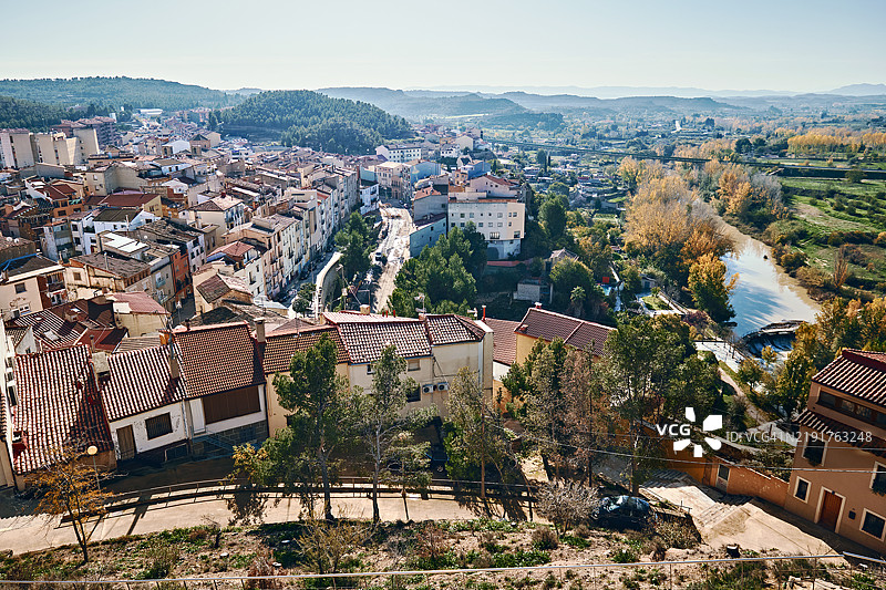 西班牙特鲁埃尔省阿尔卡尼斯风景如画的小镇鸟瞰图，周围环绕着起伏的山丘和郁郁葱葱的绿意。图片素材