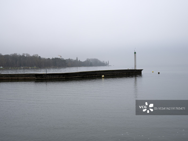 冬季日落时分，灯塔与码头上的人们图片素材