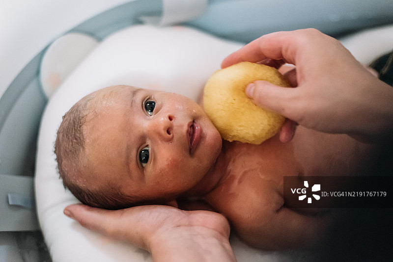 母亲在给新生儿洗澡。图片素材